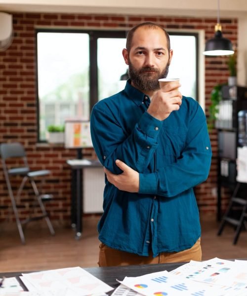portrait-of-bookkeeper-man-holding-cup-of-coffee-standing-in-startup-company-office.jpg